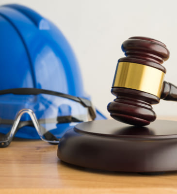 A gavel on a round stand with a hard hat and goggles
