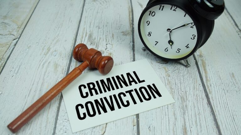 Criminal Conviction text on paper card with alarm clock and wooden judge gavel