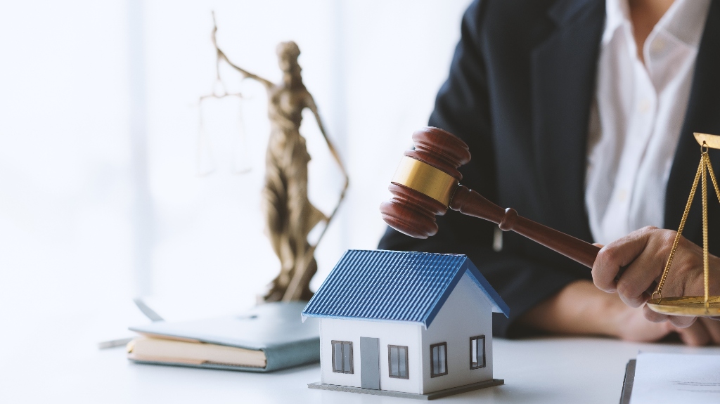 Lawyer holding judge's gavel near house model